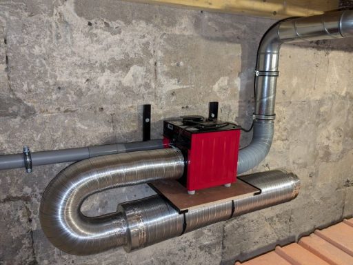 Système de ventilation avec conduits métalliques dans un sous-sol.