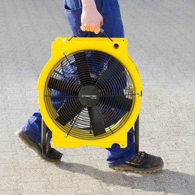 Un homme porte un ventilateur industriel jaune avec un cadre noir.